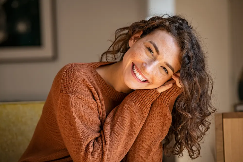 woman smiling and sitting on a sofa